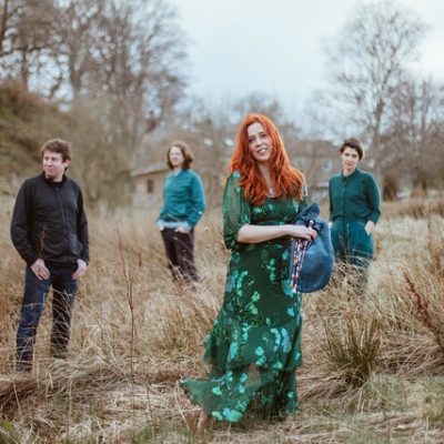 Kathryn Tickell and her band the Darkening standing in a dry grassy field